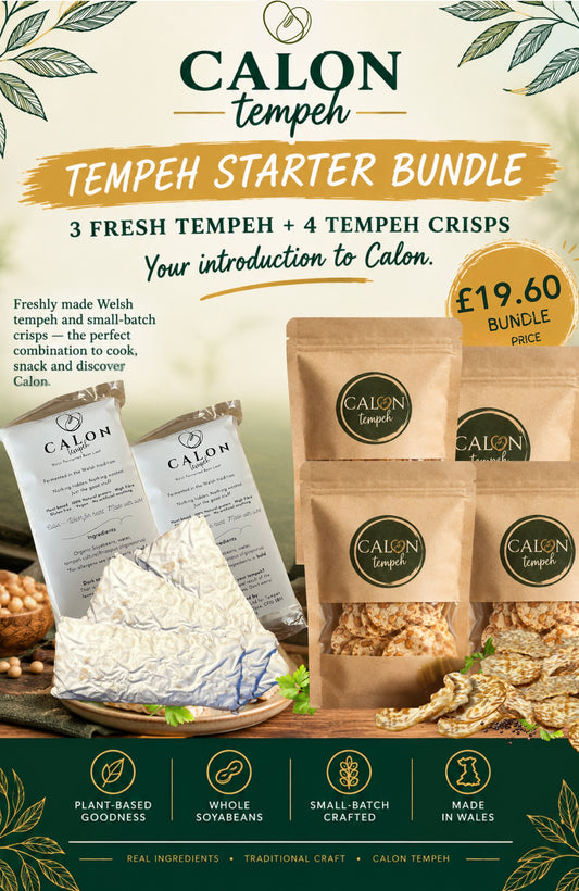 Promotional graphic for the Calon Tempeh Starter Bundle, featuring three fresh tempeh cubes and four small-batch tempeh crisps in brown paper bags on a styled wooden board. The background is cream with green leaf illustrations, and the bottom features a dark green banner with product feature icons.