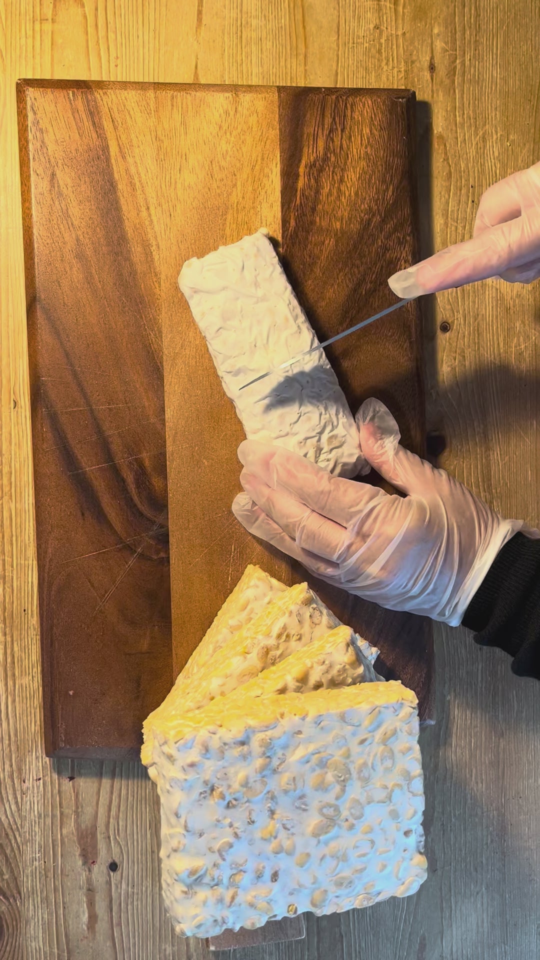 A video showing the cutting of fresh tempeh. You can a fine white network of mycelium grows through the beans and binds them together.